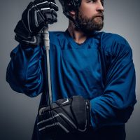 bearded ice hockey player in safety helmet holds the gaming stic